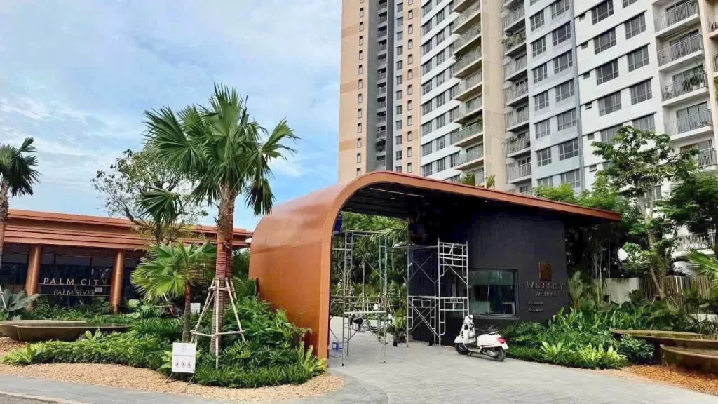 Cổng tiếp khách nhà mẫu Palm River ngày 16/08/2026, giàn giáo còn dưới mái vòm