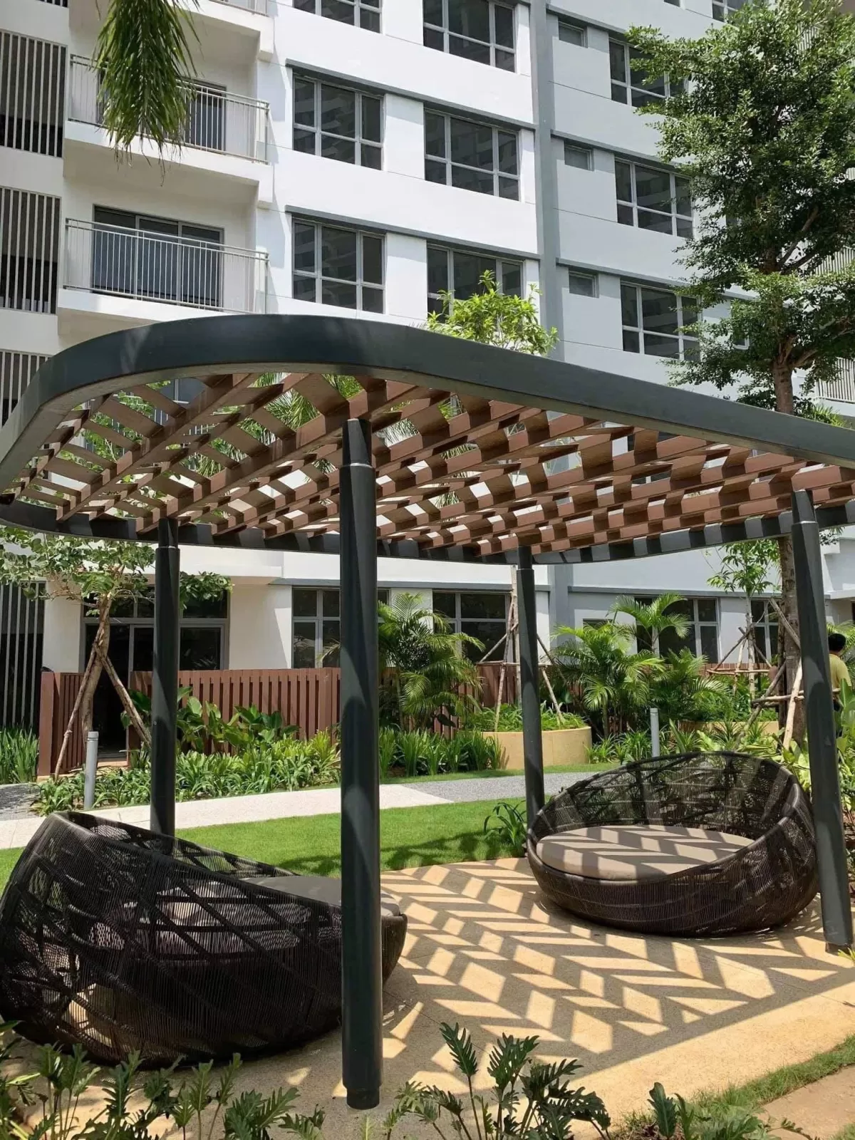 Ảnh thật chòi pergola và ghế mây trong khuôn viên tháp căn hộ Palm City