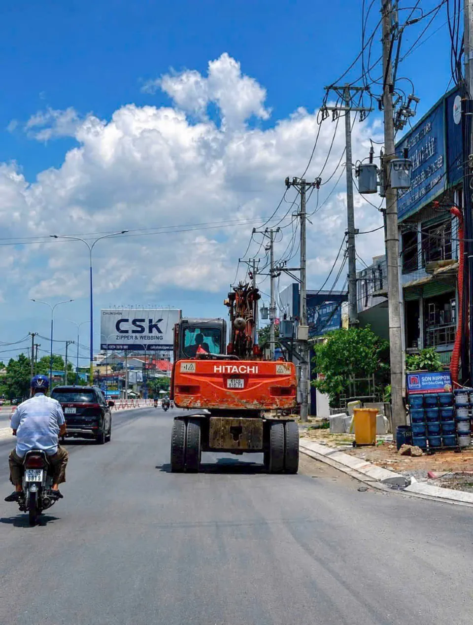 Máy xúc di chuyển trên mặt nhựa mới của Quốc lộ 13 gần dự án
